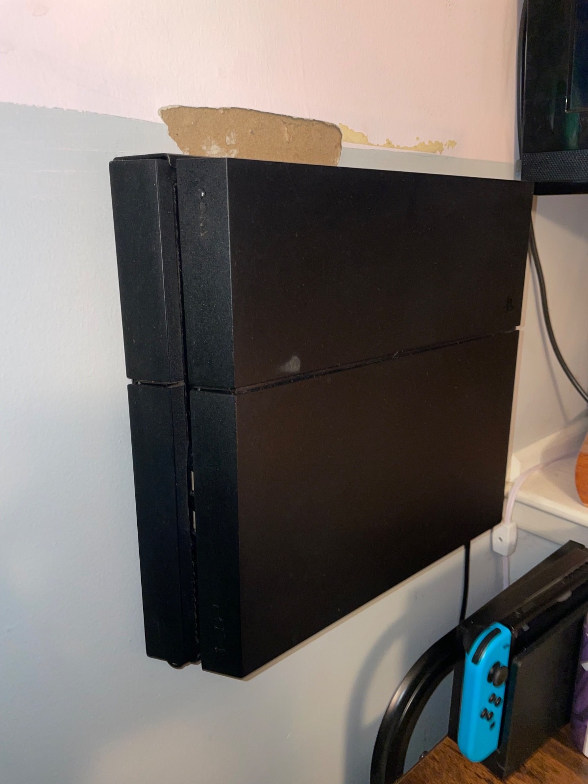 ps4 console with cords, 3 controllers, and wall mount