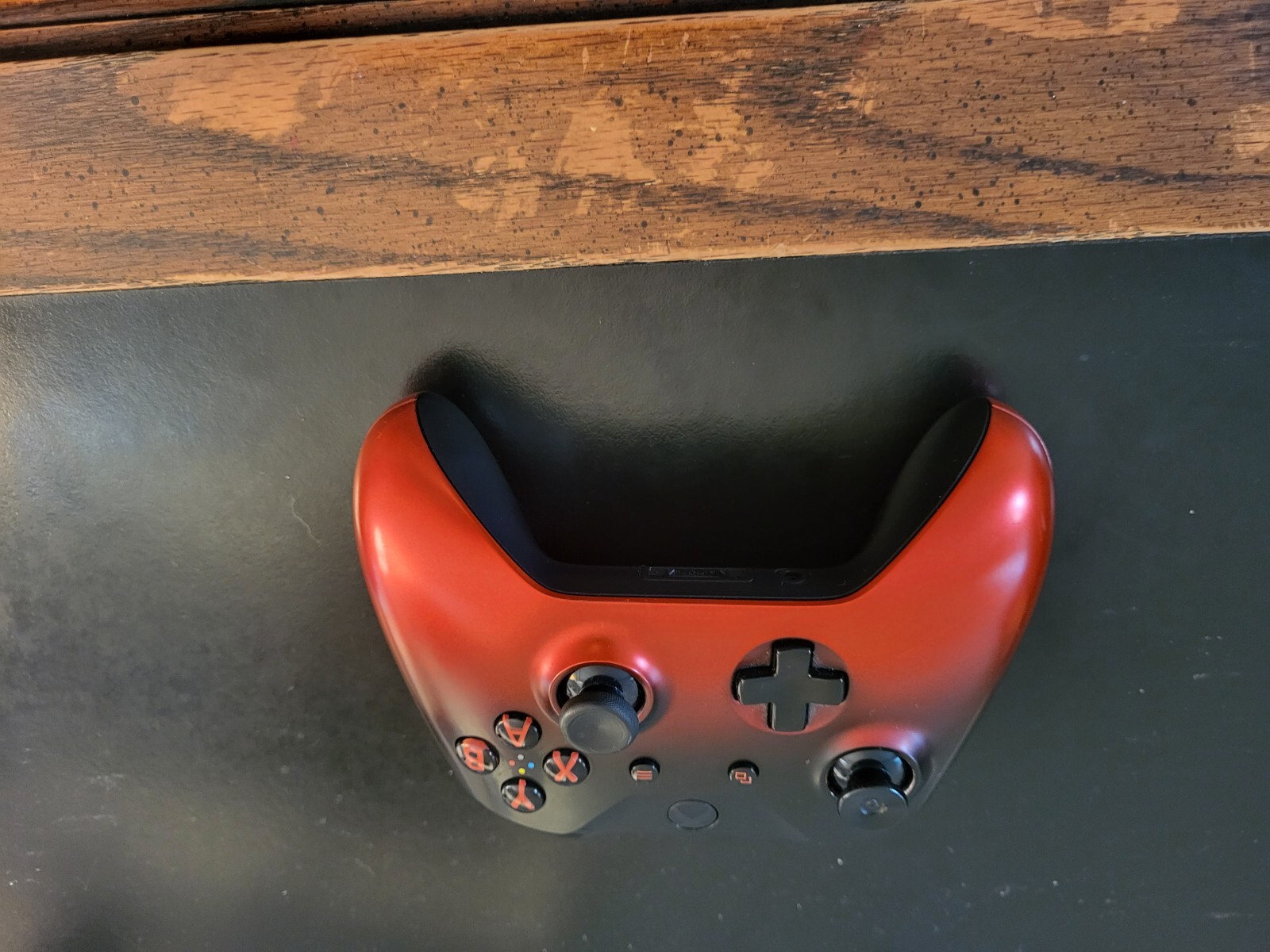 Black Xbox One Console with three wireless remotes.  Turqoise, Red, and White.